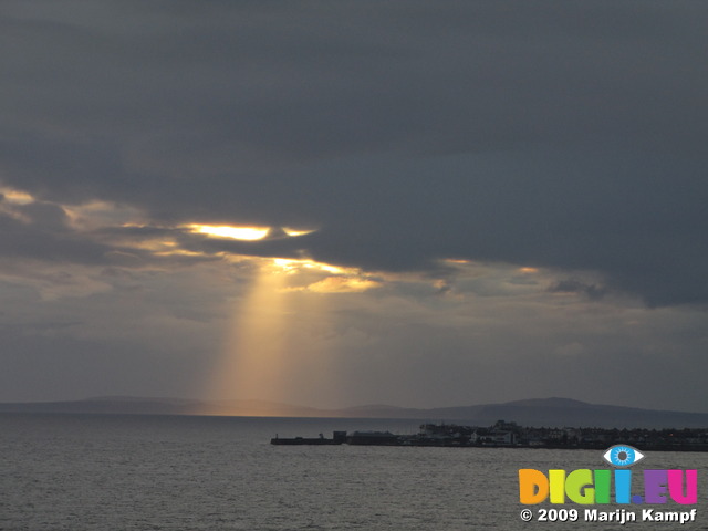 SX05561 Rays of setting sun on mumbles behind Porthcawl harbour